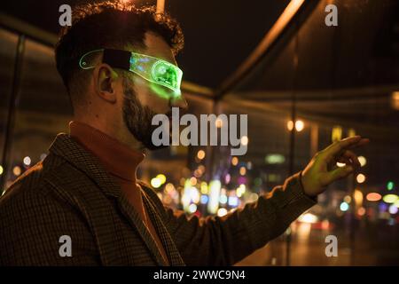 Ein Mann trägt eine kluge Brille und Gesten in der Nähe von Glas Stockfoto