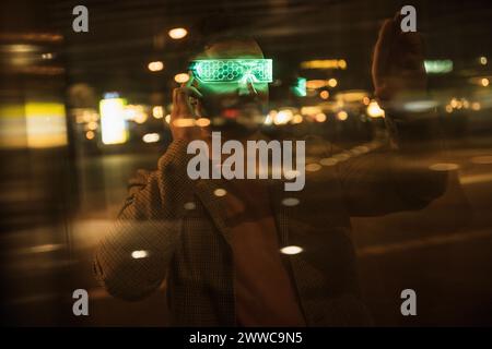 Mann mit einer intelligenten Brille, der hinter einer Glasscheibe Gesten trägt Stockfoto