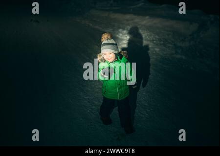 Verspielter Junge, der nachts auf Schnee steht Stockfoto