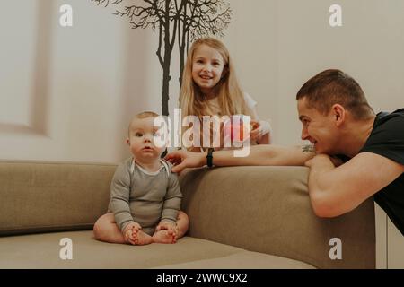 Ein Kleinkind sitzt neben der Familie auf dem Sofa zu Hause Stockfoto