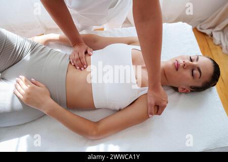 Patient, der auf dem Tisch liegt und im Behandlungsraum durch Osteopathen massiert wird Stockfoto