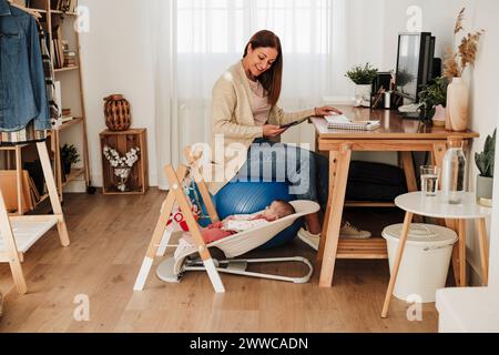 Lächelnde Mutter, die ein Mädchen auf dem Stuhl ansieht Stockfoto