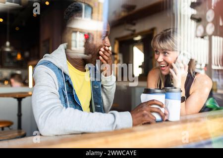 Junge multirassische Freunde, die Spaß in einem Café haben, das durch das Fenster gesehen wird Stockfoto