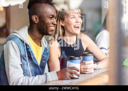 Junge glückliche Freunde, die aus dem Fenster im Café schauen Stockfoto