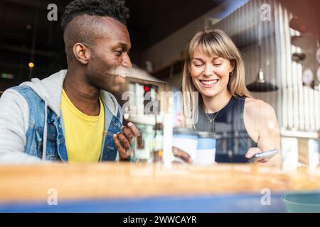Fröhliche junge Freunde, die gemeinsam im Coffee Shop genießen Stockfoto