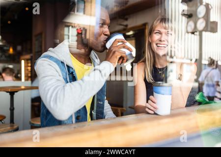 Junger Mann trinkt Kaffee mit einer Frau, die im Café telefoniert Stockfoto