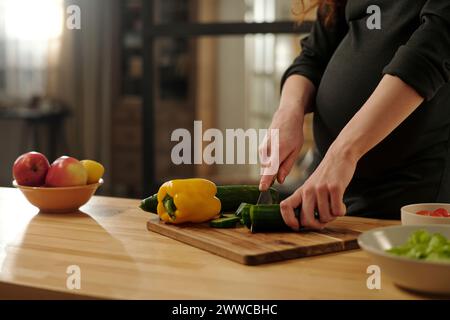 Schwangere Frau, die Gemüse in der Küche schneidet Stockfoto