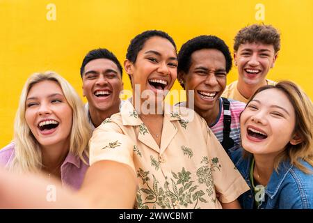 Porträt lachender multiethnischer Freunde an der gelben Wand Stockfoto