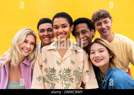 Porträt lachender multiethnischer Freunde an der gelben Wand Stockfoto