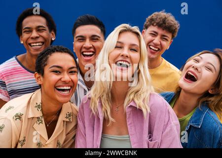 Porträt lachender multiethnischer Freunde an der gelben Wand Stockfoto