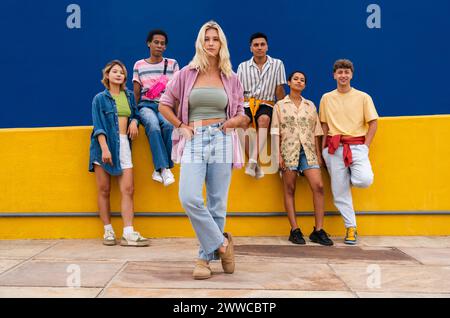 Selbstbewusste blonde Frau, die vor einer Gruppe von Freunden mit Händen auf Hüften steht Stockfoto