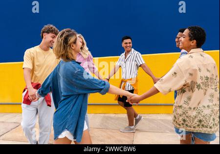 Multiethnische Gruppe von Freunden, die Hände halten und im Kreis tanzen Stockfoto