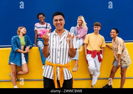 Selbstbewusster junger Mann, der vor einer Gruppe von Freunden steht und Mittelfinger zeigt Stockfoto