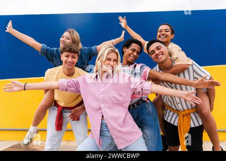 Gruppe junger Freunde mit bunten Kleidern posiert fröhlich vor der Wand Stockfoto