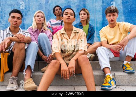 Selbstbewusste junge Menschen, die auf Stufen vor der Wand sitzen Stockfoto