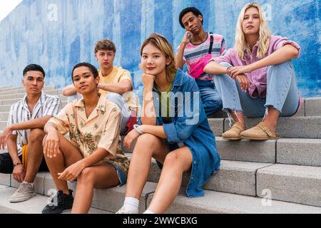 Selbstbewusste junge Menschen, die auf Stufen vor der Wand sitzen Stockfoto