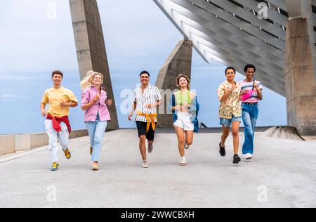 Vielfältige Gruppe junger Freunde mit bunten Kleidung, die Spaß beim Laufen im Freien haben Stockfoto