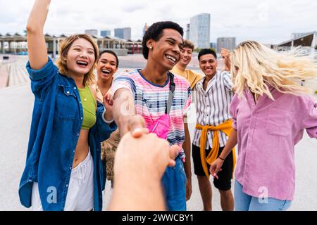 Glückliche junge Freunde, die Hände halten und Spaß haben Stockfoto