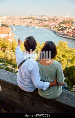 Mann, der mit einer Frau vor dem Fluss Douro in Porto in Portugal sitzt Stockfoto