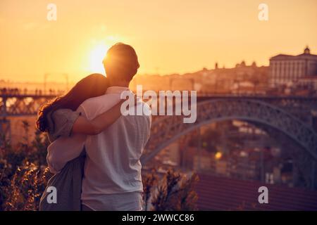 Junge Paare, die sich bei Sonnenuntergang vor der Dom Luis Brücke umarmen, Porto, Portugal Stockfoto