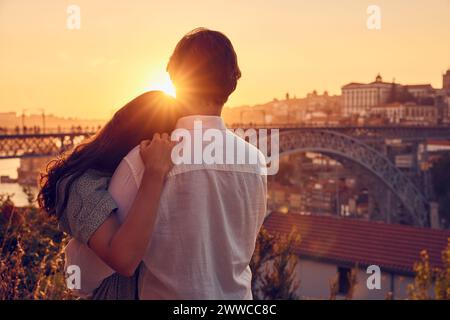 Liebevolles Paar, das sich vor der Dom Luis Brücke bei Sonnenuntergang umschließt, Porto, Portugal Stockfoto