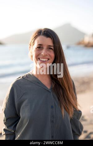 Glückliche Frau in grauem Hemd am Strand an sonnigem Tag Stockfoto
