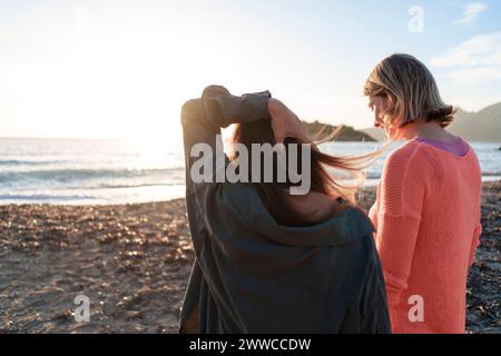Freunde, die am Wochenende zusammen am Strand spazieren gehen Stockfoto