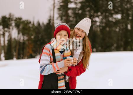 Glückliche Mutter und Sohn tragen warme Kleidung im Winterwald Stockfoto