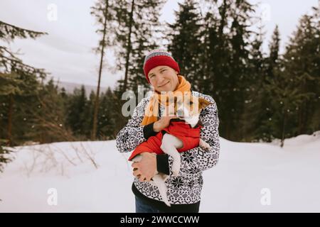 Lächelnder Mann mit Hund im Winterwald Stockfoto