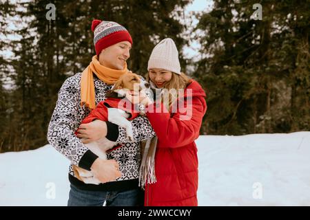 Glückliches Paar mit Hund im Winterwald Stockfoto