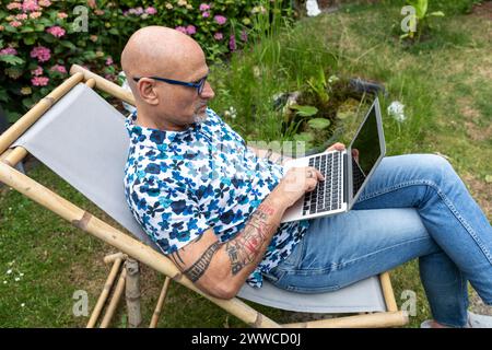 Reife Freiberufler tippen auf Laptop im Garten Stockfoto