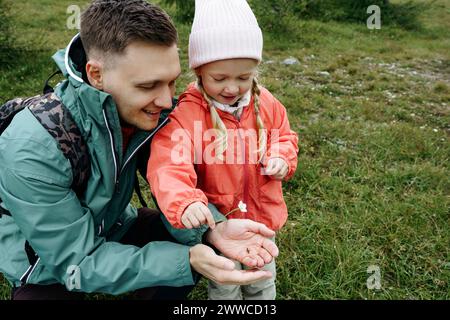 Lächelnder Vater zeigt Käfer und Blume der Tochter Stockfoto