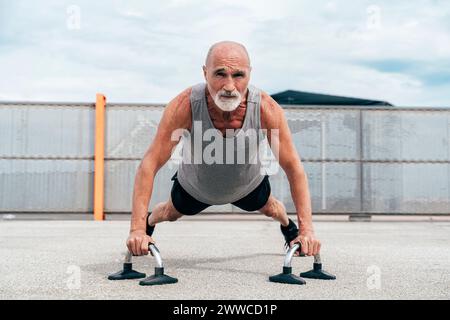 Aktiver Senior-Mann, der Plank-Übungen an Griffen macht Stockfoto