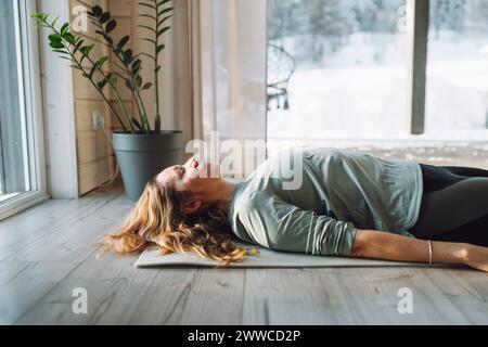 Eine reife Frau, die zu Hause Leichen auf der Trainingsmatte posiert Stockfoto