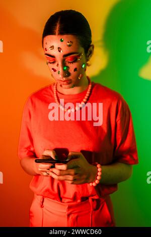 Frau, die ein Smartphone vor farbenfrohen Hintergrund benutzt Stockfoto