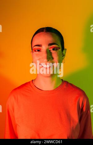Lächelnde Frau in rotem T-Shirt vor orangem Hintergrund Stockfoto