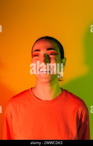 Glückliche junge Frau in Neonlicht vor verlaufendem Hintergrund Stockfoto
