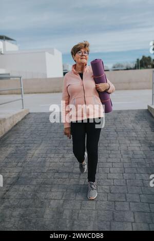 Ältere Frau mit Trainingsmatte, die auf dem Gehweg läuft Stockfoto