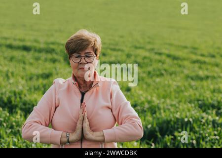 Eine ältere Frau, die Yoga auf der Wiese praktiziert Stockfoto