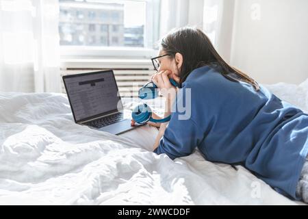 Programmiergerät mit Laptop, der zu Hause auf dem Bett liegt Stockfoto