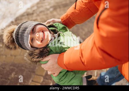 Lächelnder Junge im Parka-Mantel, der im Winter mit dem Vater steht Stockfoto