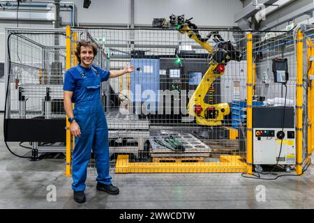 Lächelnder Wartungstechniker, der den Roboterarm in einer modernen Fabrik anspricht Stockfoto