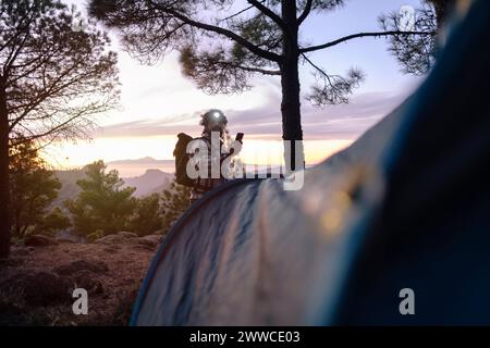 Mann mit Stirnlampe und Smartphone bei Sonnenuntergang in der Nähe von Bäumen Stockfoto