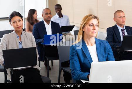 Konzentrierte Geschäftsleute, die während eines Geschäftsseminars an Laptops arbeiten Stockfoto