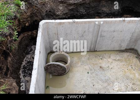 Klärgrube aus Beton mit einer Kapazität von 10 m3 im Garten neben dem Haus, ohne Abdeckung. Stockfoto