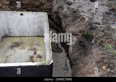 Klärgrube aus Beton mit einer Kapazität von 10 m3 im Garten neben dem Haus, sichtbarer wasserdichter Klebstoff für die Abdeckung. Stockfoto