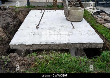 Klärgrube aus Beton mit einer Kapazität von 10 m3 im Garten neben dem Haus, sichtbare Abdeckung mit Mannloch. Stockfoto