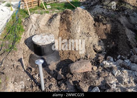 Mit einem Bagger eine 10 m3 große Klärgrube aus Beton im Garten neben dem Haus begraben. Stockfoto
