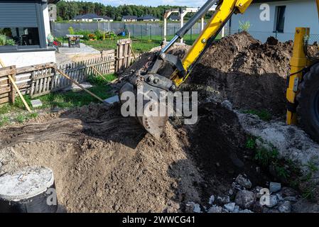 Mit einem Bagger eine 10 m3 große Klärgrube aus Beton im Garten neben dem Haus begraben. Stockfoto