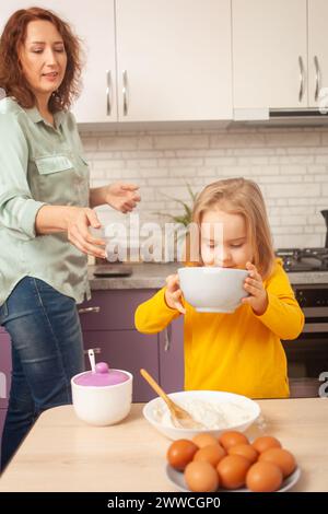 Großmutter und Enkelin machen Kuchen in der Küche, glückliche Familie, Frau und Kind lächeln. Schüssel Stockfoto